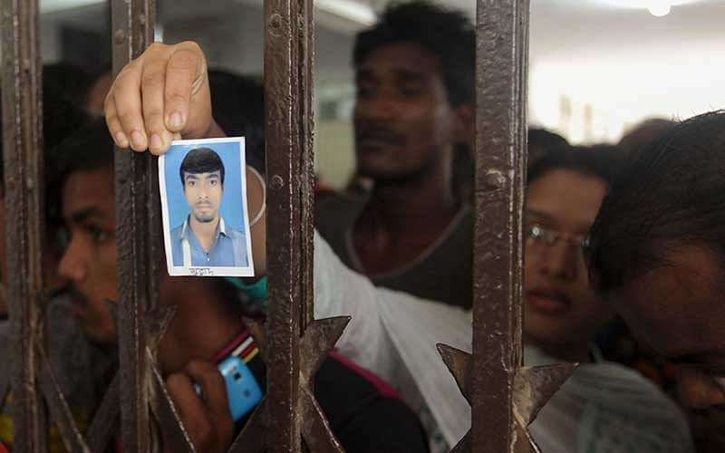 A relative of a Bangladeshi factory worker holds up his picture at a building where their bodies were brought after an explosion in a factory in the key Bangladeshi garment manufacturing town of Tongi, just north of the capital Dhaka, on September 10, 2016. Photo: AFP