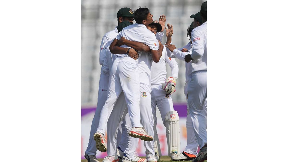 Bangladesh`s Taijul Islam (C) with teammates celebrate after taking the wicket of England Ben Stokes during the second day of the second Test cricket match in Dhaka. Photo: AFP