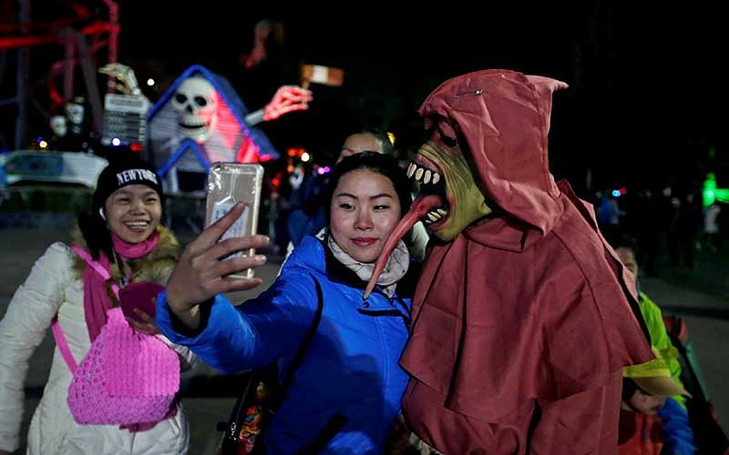 A woman takes a selfie with a performer during a Halloween parade at Happy Valley park in Beijing, China. Photo: Reuters