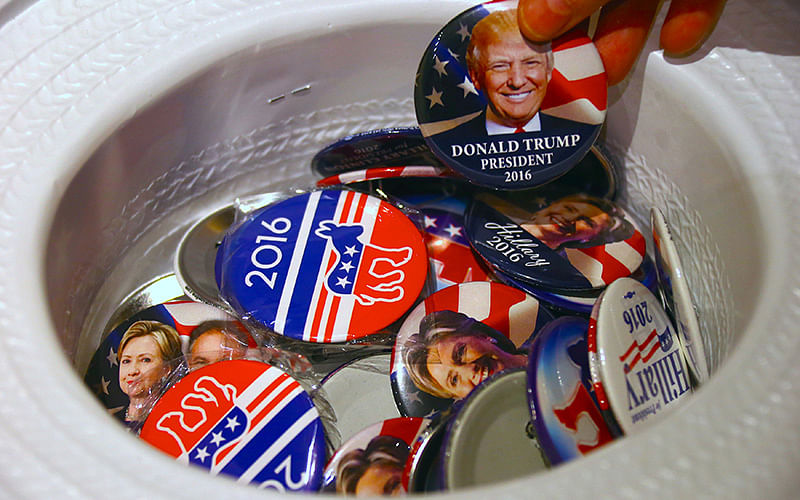 A guest at an event called the US Presidential Election Watch, organised by the US Consulate, reaches for a badge from out of a hat displaying photographs of Republican candidate Donald Trump and Democratic candidate Hillary Clinton, in Sydney. Photo: Reuters