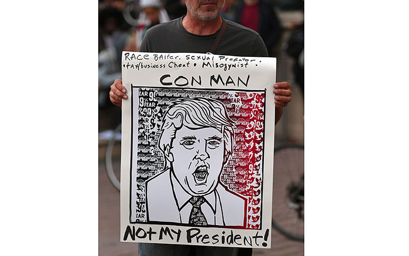 Joel Cook holds a sign during an anti-Trump protest in Oakland, California on November, 9, 2016. Photo: AFP