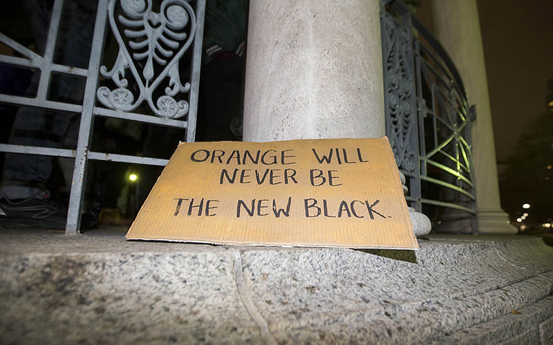 A sign left by a protester that reads `Oranage Will Never Be The New Black` at a protest against the elction of Donald Trump in the Boston Common on November 9, 2016 in Boston, Massachusetts. Trump defeated Democrat Hillary Clinton in an upset to become the 45th president. Photo: AFP