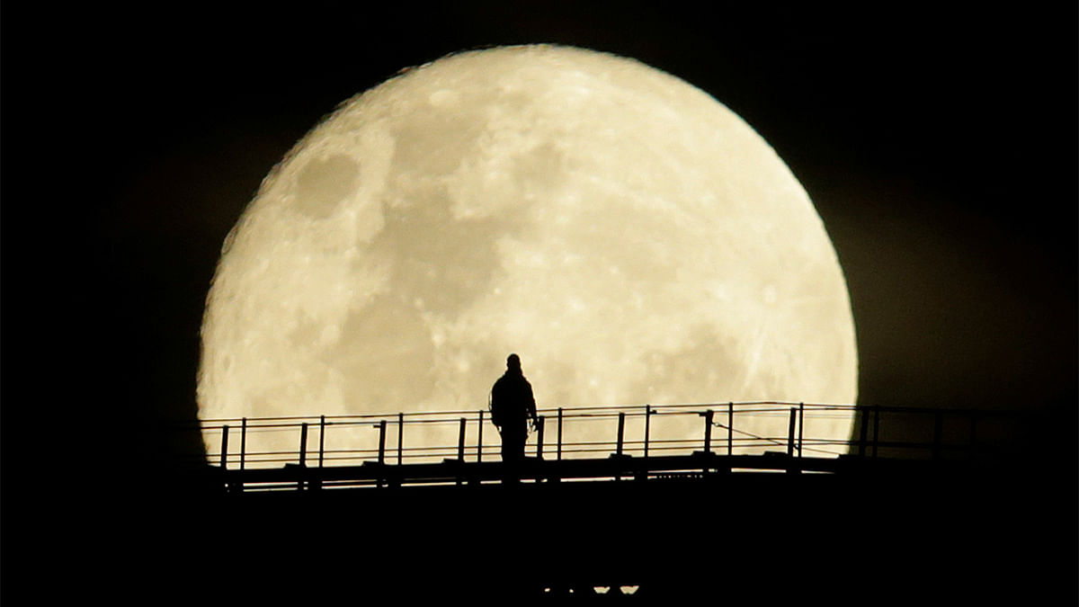 A man walks on the top span of the Sydney Harbour Bridge as the supermoon enters its final phase in Sydney. Reuters