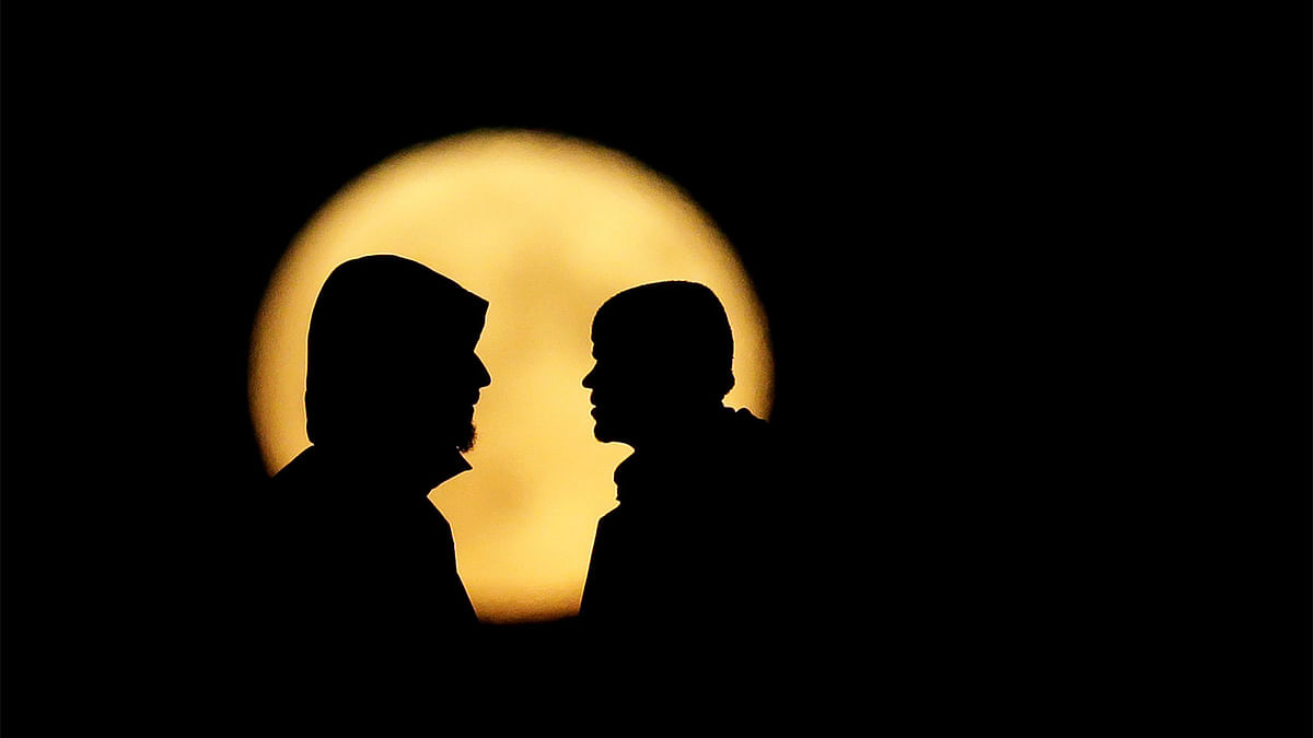 People are silhouetted against the supermoon in Prague. Reuters