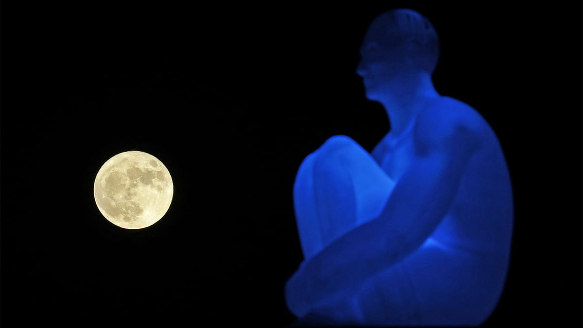 The supermoon rises behind one of the seven statues by spanish artist Jaume Plensa on Massena square in Nice. Reuters