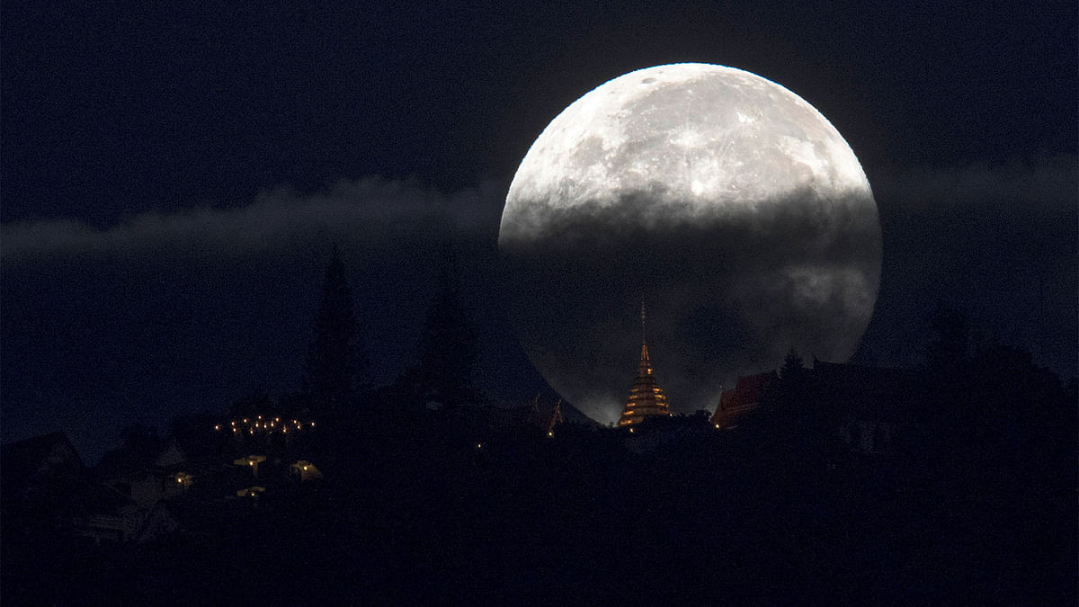 The supermoon is partly covered by clouds as it sets behind Wat Phrathat Doi Suthep in the northern capital of Chiang Mai, Thailand, November 15, 2016. Reuters