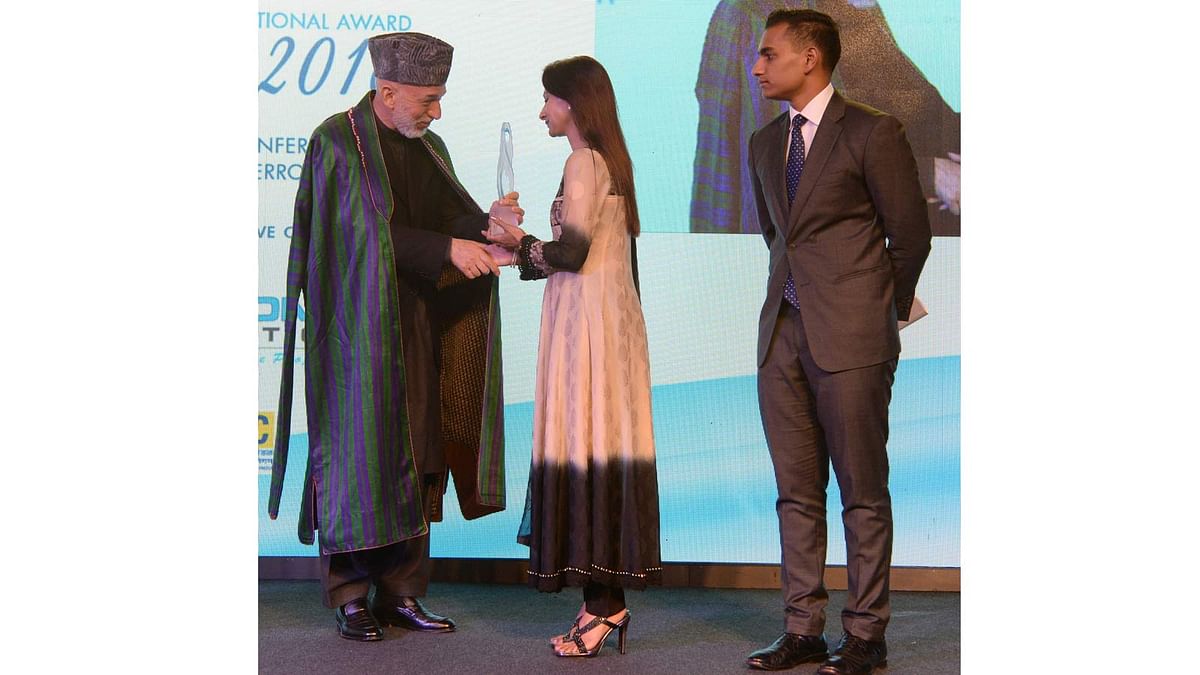 Simeen Hossain (C), watched by her elder son Zaraif (R) receives the Mother Teresa Memorial International Award for Social Justice 2016 from former Afghan President Hamid Karzai, on behalf of her martyred son Faraaz Ayaaz Hossain at an award ceremony in Mumbai on 20 November 2016. Photo: AFP