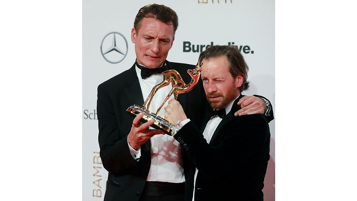 German actors Oliver Masucci and Fabian Busch pose for photographers with the trophy at the Bambi awards on November 17, 2016 in Berlin. The Bambis are the main German media awards. Photo: AFP
