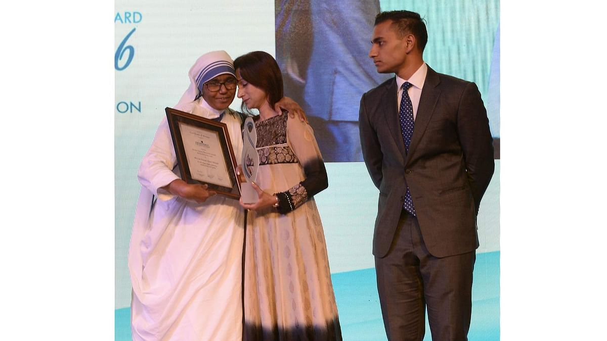 Simeen Hossain (C), watched by her elder son Zaraif (R) receives the Mother Teresa Memorial International Award for Social Justice 2016 from from Sister Priscila of Missionaries of Charity, on behalf of her martyred son Faraaz Ayaaz Hossain at an award ceremony in Mumbai on 20 November 2016. Photo: AFP
