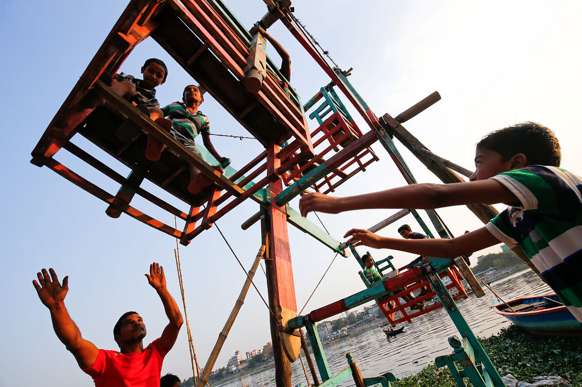 Children enjoy a manual whirligig ride in the afternoon in Dhaka, Bangladesh. Photo: Reuters