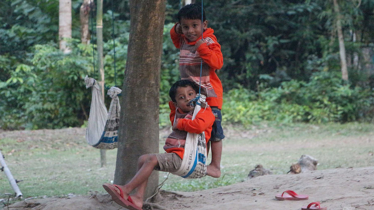 Joys cannot be rob off from children. Two boys ride in a swing made out of burlap sack in                                        khulna`s Shiromoni area. Photo:  Saddam Hossain