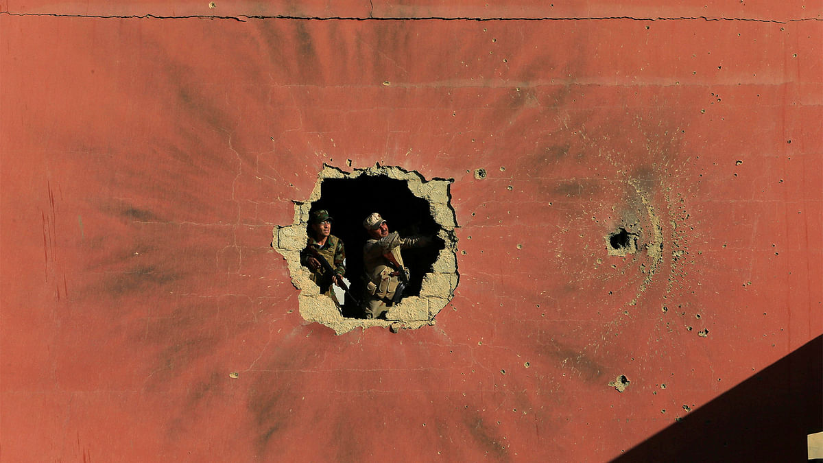 Policemen look through a hole in a house from the clashes in Qaraqosh, near Mosul, Iraq, December 9, 2016. Picture taken December 9, 2016. Photo: Reuters