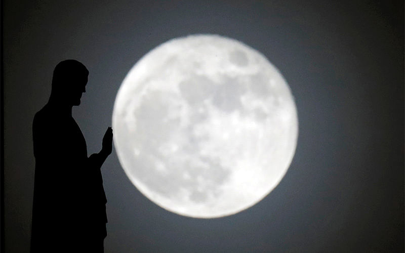 A statue on the roof of Notre-Dame cathedral is silhouetted in front of a supermoon in Paris, France, December 14, 2016. Photo: Reuters