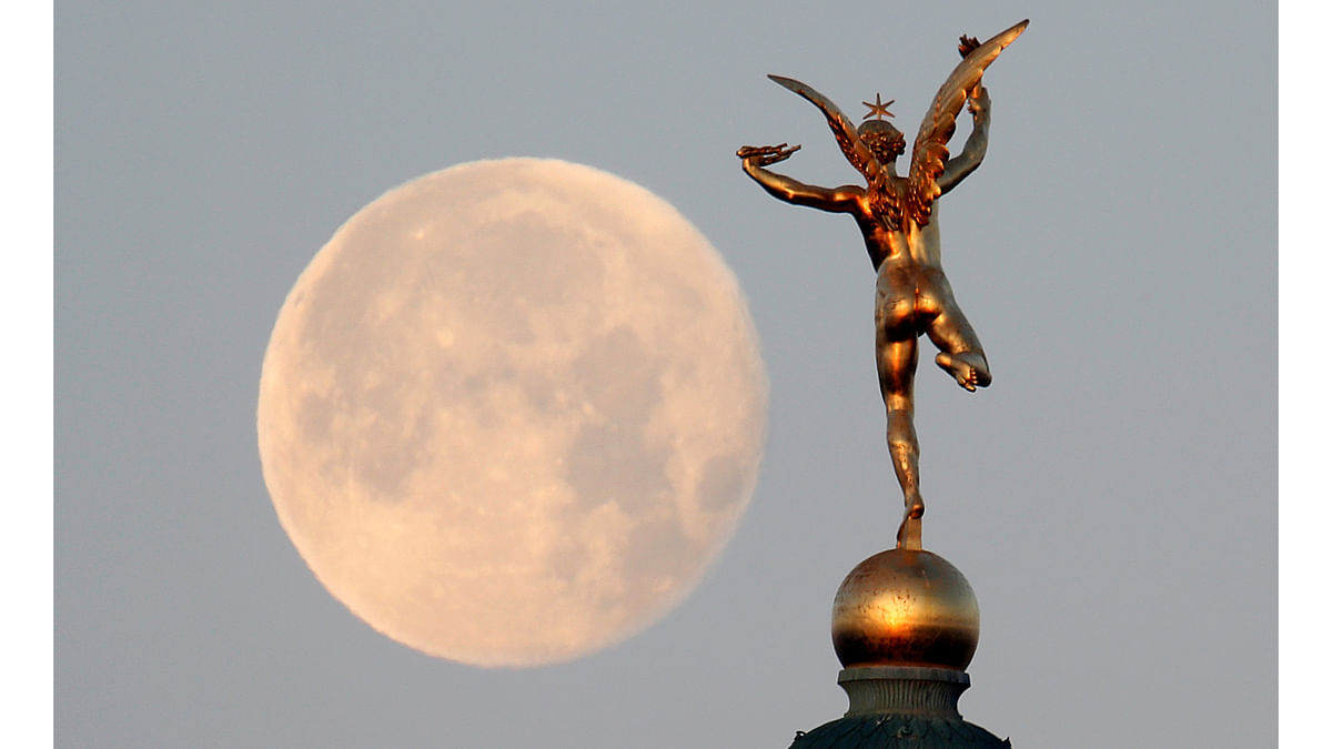 The moon is seen behind the `Genie de la Liberte` gilded figure (Spirit of Freedom) on top of the Place de la Bastille`s July Column in Paris, France, December 15, 2016. Photo: Reuters