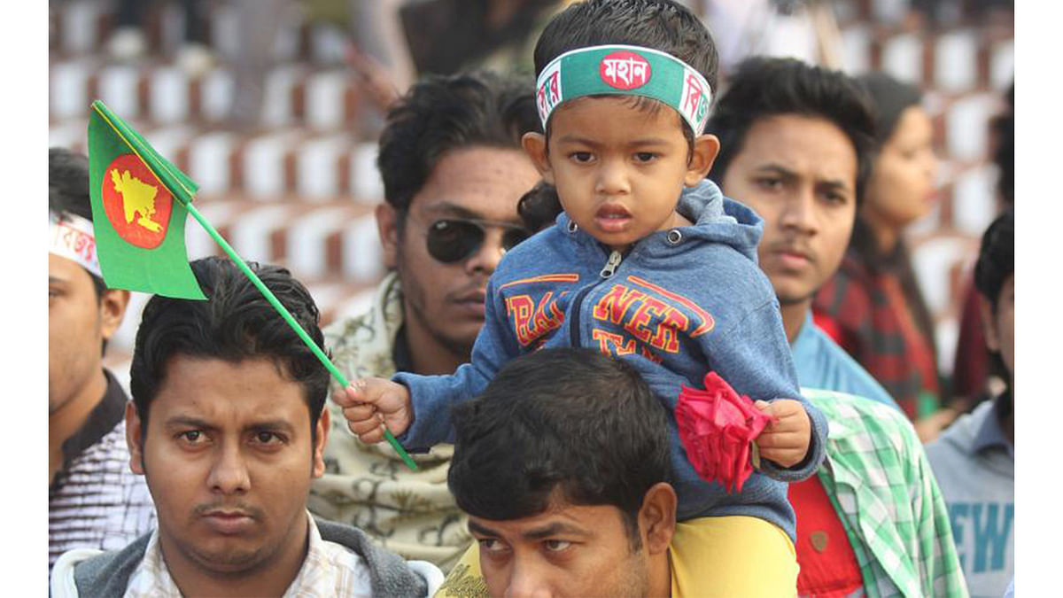 A child on his father’s shoulder, hoisting a mini flag of Bangladesh at  at the National Memorial on 16 December. Photo: Abdus Salam