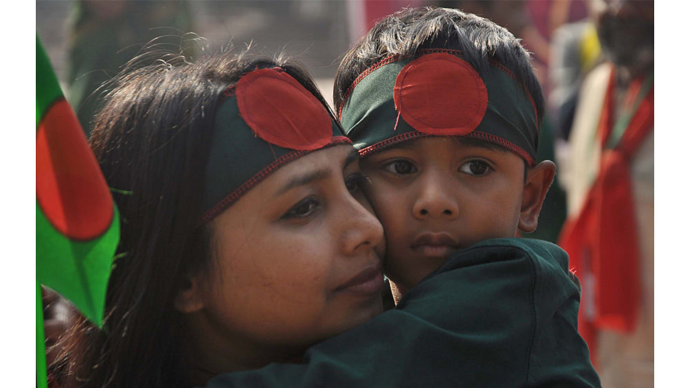 A kid and a woman wear bands of national flag during a rally at Central Shaheed Minar celebrating the 46th Victory Day on Friday. Photo: Focus Bangla
