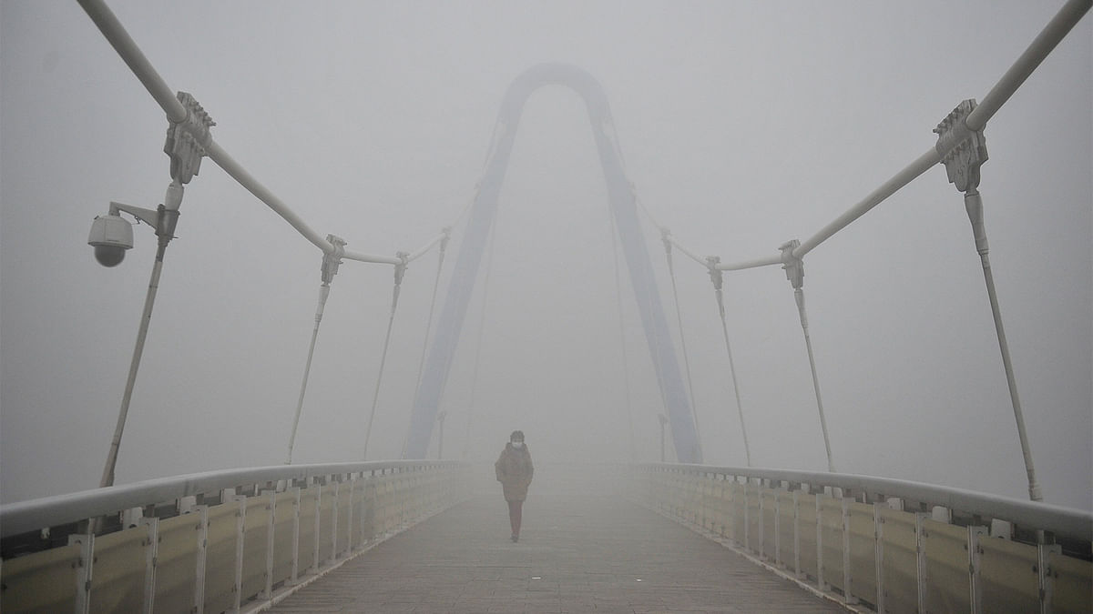 A woman wearing a mask walks along a bridge in smog during a polluted day in Tianjin, China, December 19, 2016. Photo: Reuters
