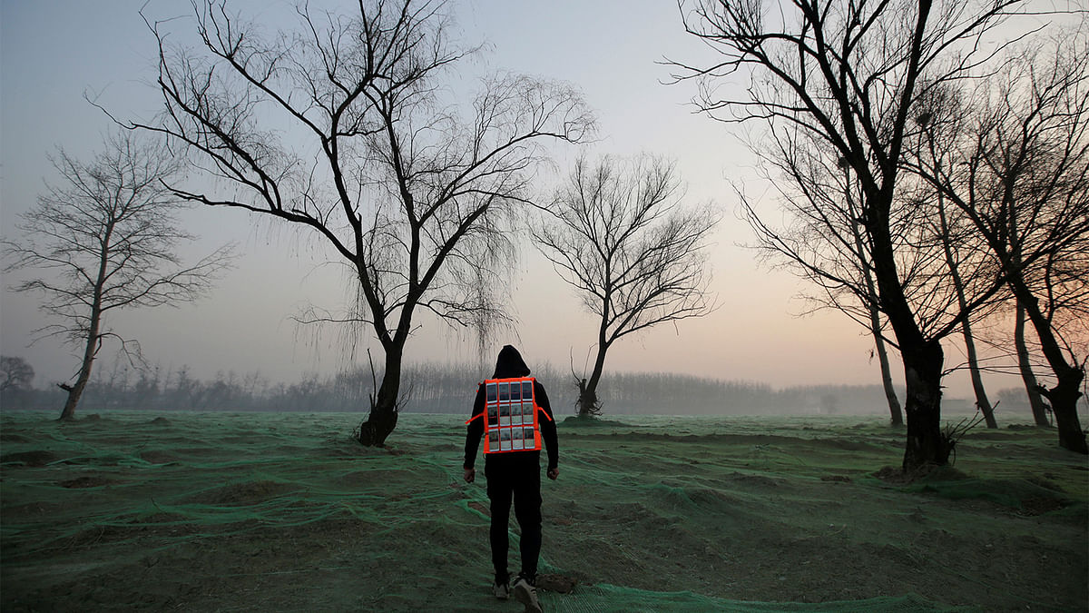 Artist Liu Bolin wearing a vest with 24 mobile phones walks in smog as he live broadcasts air pollution in the city on the fourth day after a red alert was issued for heavy air pollution in Beijing, China, December 19, 2016. Photo: Reuters