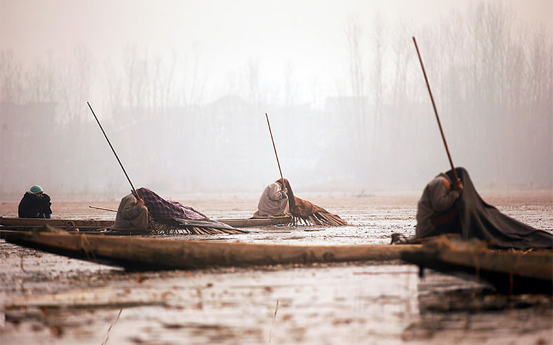 Kashmiri fishermen cover their heads and part of their boats with blankets and straw as they wait to catch fish in the waters of the Anchar Lake on a cold day in Srinagar, December 20, 2016. Photo: Reuters