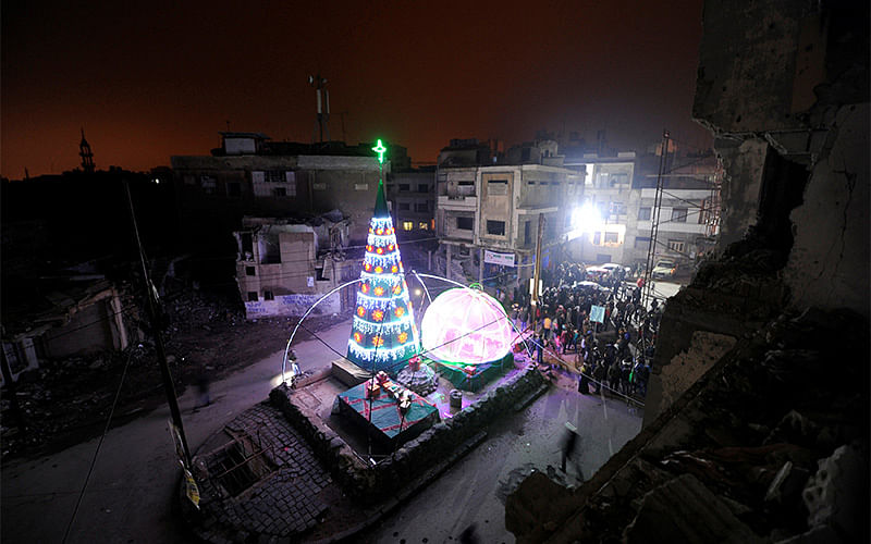 People gather by a Christmas tree near damaged buildings during Christmas eve in al-Hamidiyah neighbourhood in the old city of Homs, Syria. Photo: Reuters