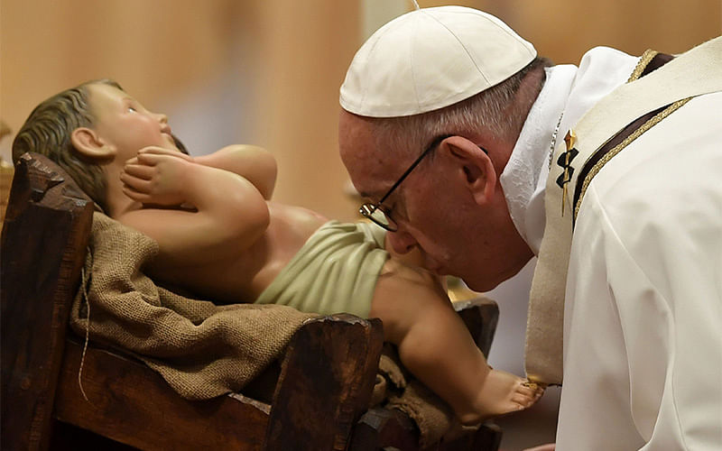 Pope Francis kisses a figurine of baby Jesus as he celebrates a mass on Christmas eve marking the birth of Jesus Christ on December 24, 2016 at St Peter`s basilica in the Vatican. Photo: Reuters