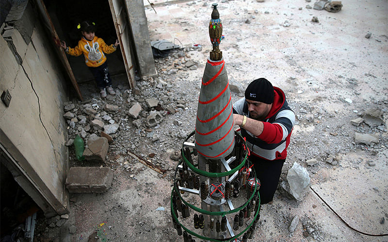Akram Abu al-Foz, decorates a christmas tree from empty shells he collected and drew on, in the rebel held besieged city of Douma. Photo: Reuters
