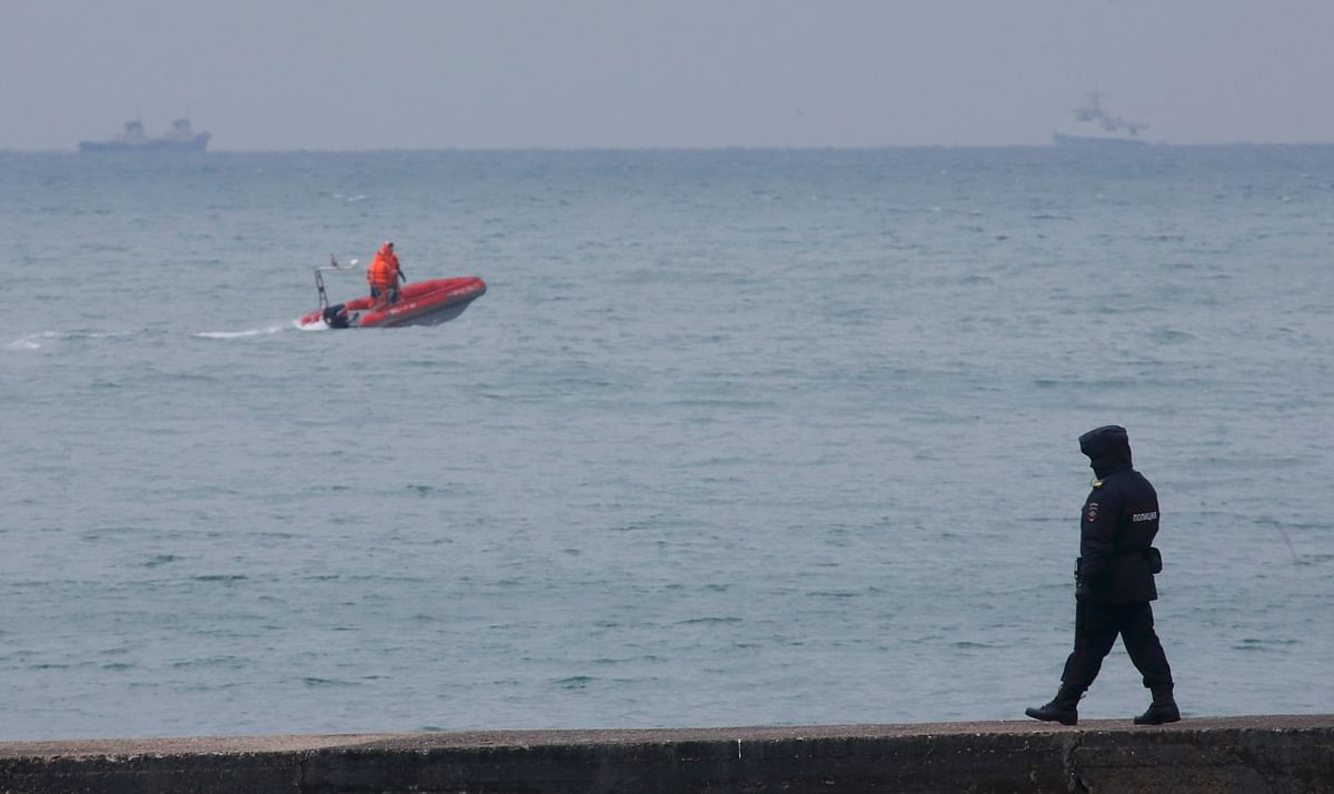 Police officer walks on pier as boat of Russian Emergencies Ministry sails near crash site of Russian military Tu-154 plane in Black Sea in Sochi suburb of Khosta. Reuters