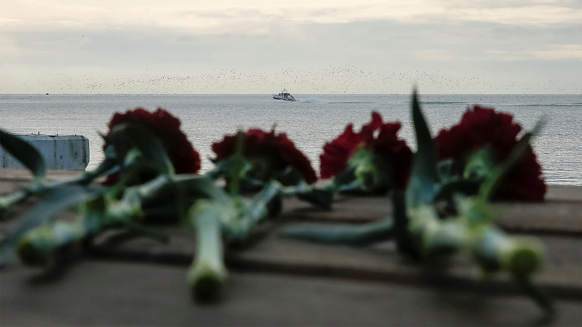 Flowers are placed on a pier as a boat of Russian Emergencies Ministry sails near the crash site of a Russian military Tu-154 plane, which crashed into the Black Sea on its way to Syria on Sunday, in the Black Sea resort city of Sochi, Russia, December 26, 2016. Photo: Reuters