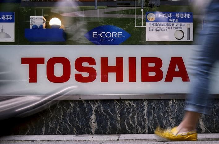 Pedestrians walk past a logo of Toshiba Corp outside an electronics retailer in Tokyo. Reuters file photo