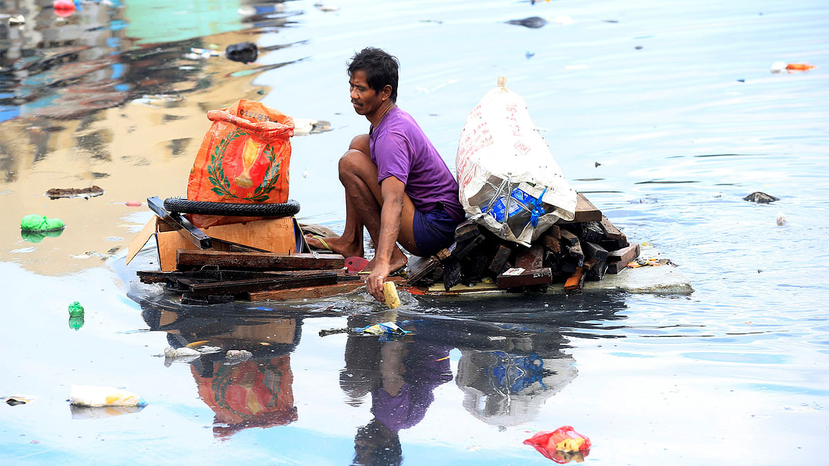 A man uses an improvised banca to collect plastic materials in a polluted river in Manila, Philippines December 24, 2016. Photo: Reuters