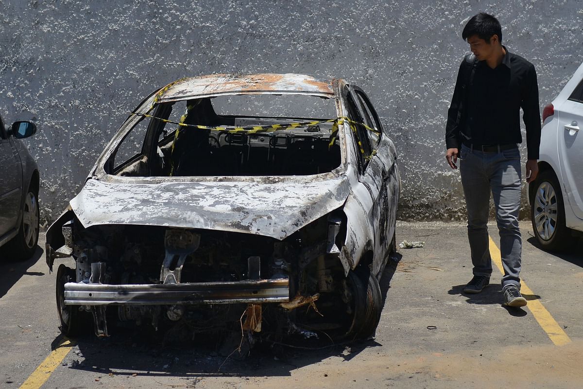 A man looks at the burned-out rental car of missing Greek ambassador to Brazil Kyriakos Amiridis, at a parking lot outside the police station in Belford Roxo, in the Brazilian state of Rio de Janeiro, on December 30, 2016, a day after it was found with a body inside. Photo: AFP