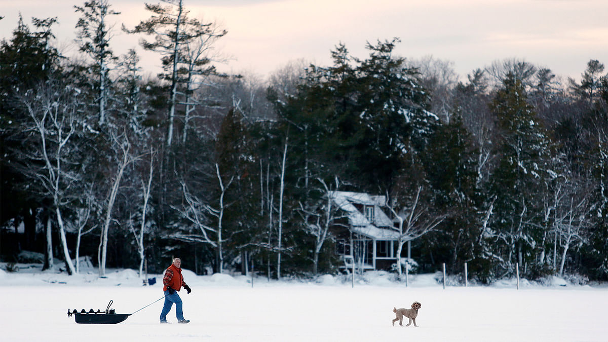 A man and his dog look for places to place ice fishing traps on Pushaw Lake in Orono, Maine, US. Photo: Reuters