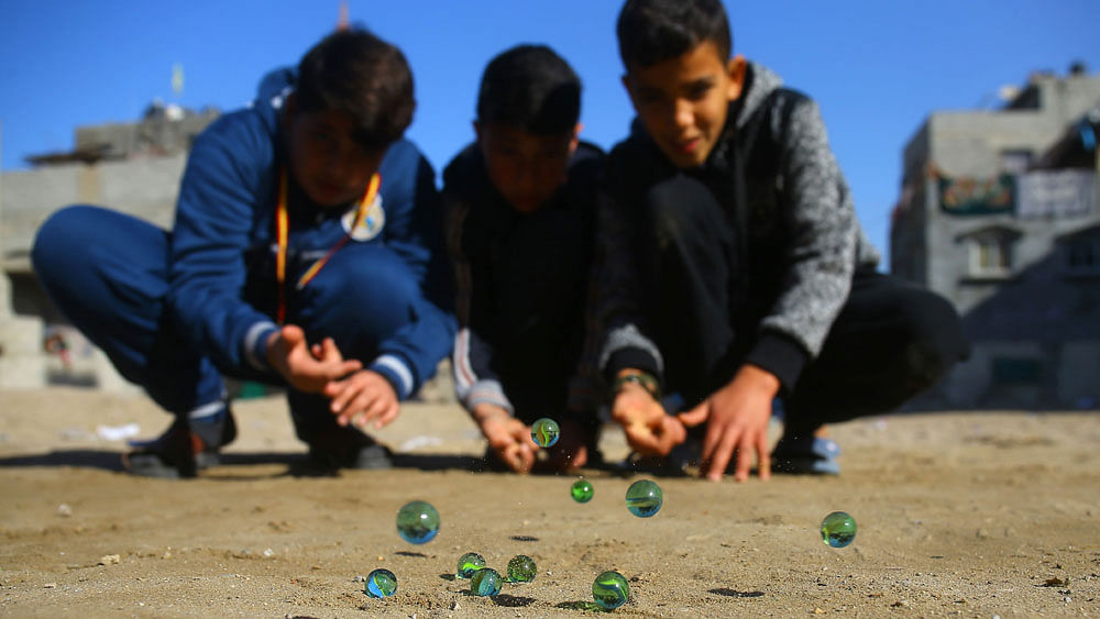 Palestinian children play marbles in a street in Gaza City on January 11, 2017. AFP