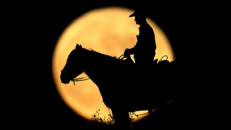 A full moon rises behind U.S. Border Patrol agent Josh Gehrich as he sits atop a hill while on patrol near Jacumba, California, US. Reuters