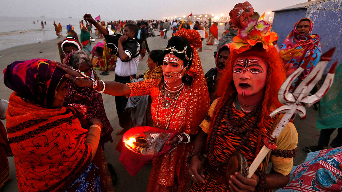 Two Indian men dressed as Hindu Lord Shiva (R) and Goddess Parvati (C) give blessings to a pilgrim at the confluence of the river Ganges and the Bay of Bengal, ahead of the `Makar Sankranti` festival at Sagar island, south of Kolkata, India January 13, 2017. Photo: Reuters