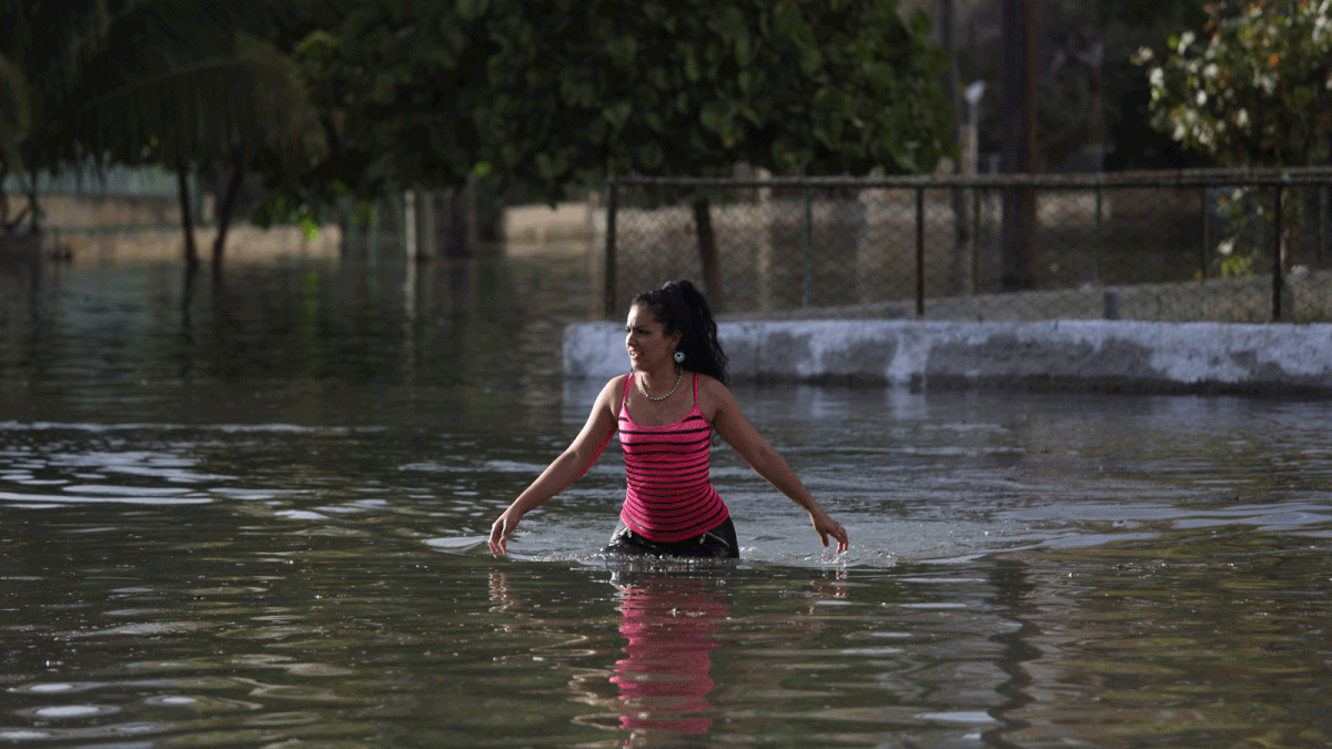 A woman makes her way on a flooded street in Havana, Cuba. Photo: Reuters