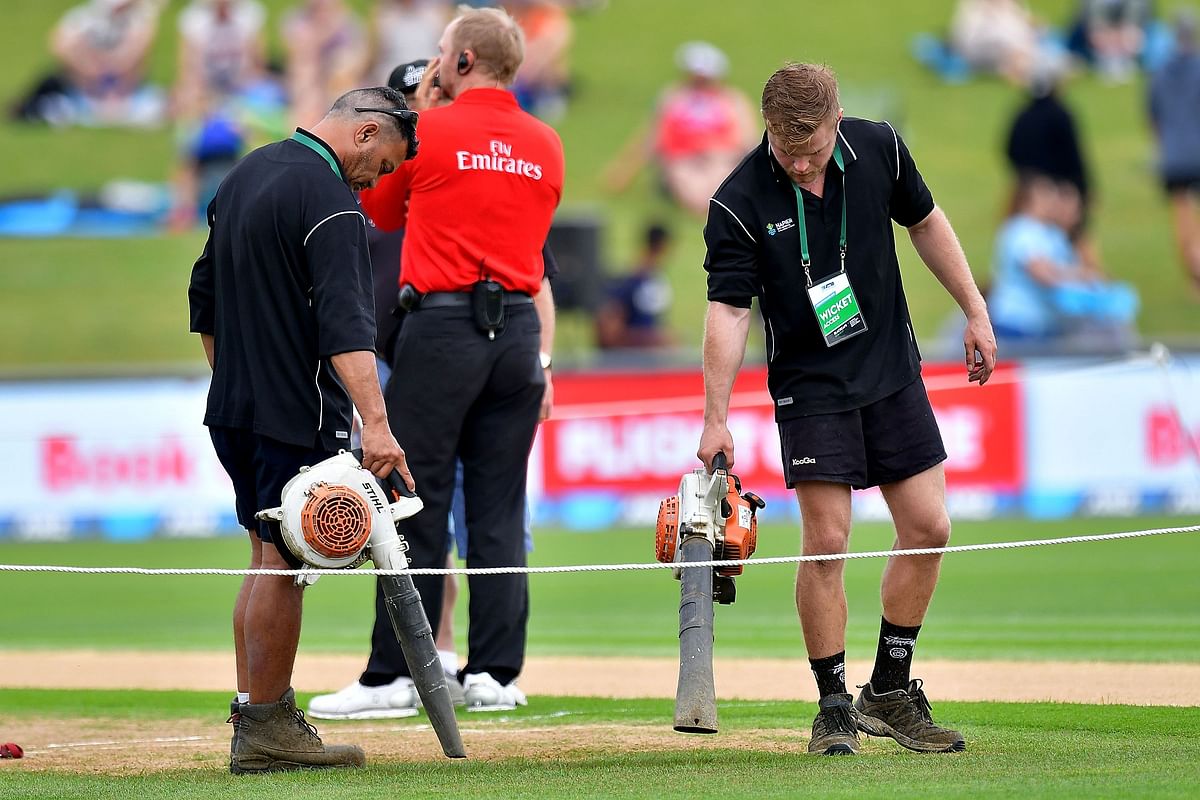 Grounds staff use leaf blowers to dry the wicket as rain delays the start of the 2nd one-day international cricket match between New Zealand and Australia at McLean Park in Napier on February 2, 2017. AFP