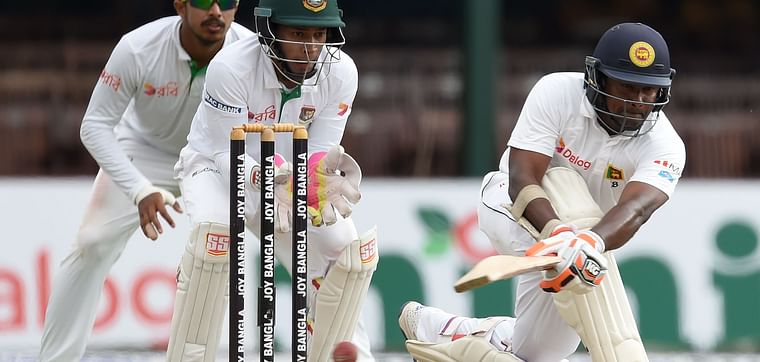 Sri Lanka's captain Rangana Herath (R) plays a shot as Bangladesh captain Mushfiqur Rahim (C) looks on.
