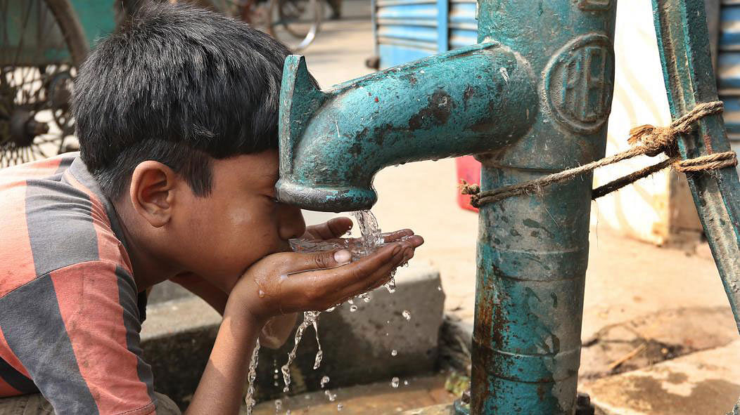 A boy drinks water from a tube well that keeps pouring water most of the time. The photo was taken at Hussaini Dalan area in Old Town of Dhaka on 21 March. Photo: Abdus Salam.