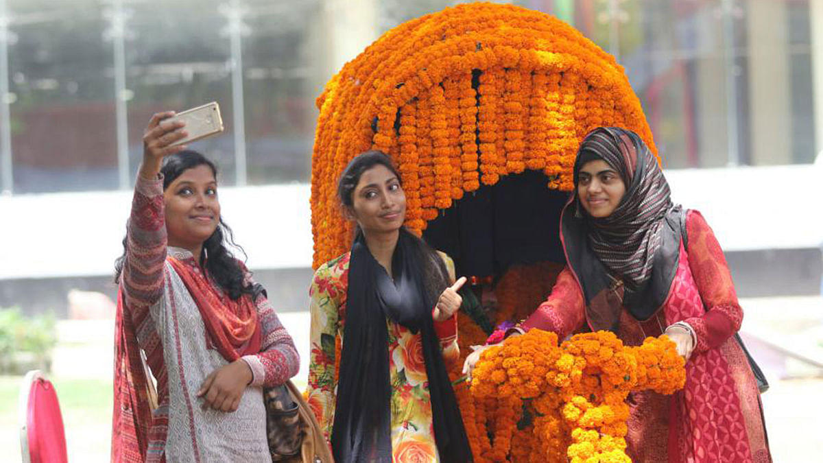 Women take a picture with a rickshaw decorated with flowers at flower festival at  Bangla Academy. Photo: Abdus Salam