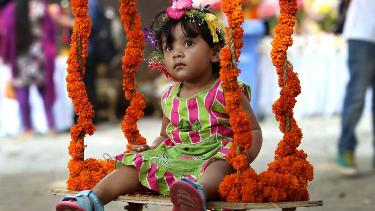 Swing! Swing! A child stares while swaying on a swing at flower festival at  Bangla Academy. Photo: Ashraful Alam