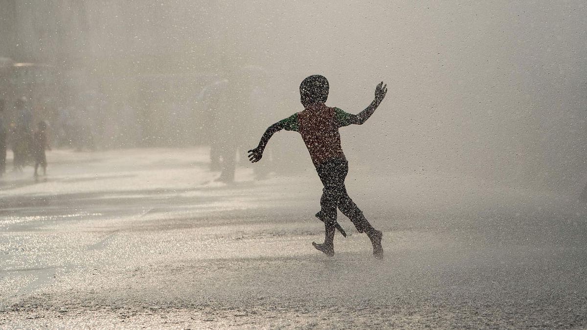 A boy plays under spraying water coming from jets installed in front of Yangon`s city hall on April 12, 2017, during a test run by authorities on the eve of the water festival known as Thingyan.Photo: AFP