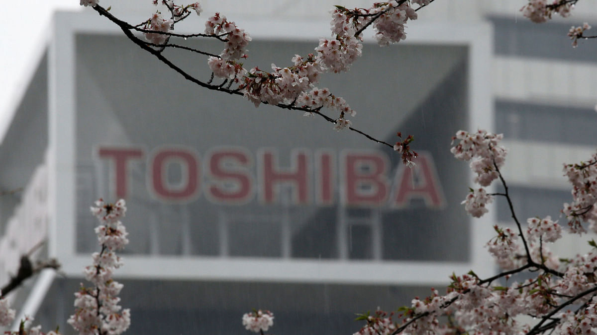 The logo of Toshiba Corp is seen behind cherry blossoms at the company`s headquarters in Tokyo. Reuters