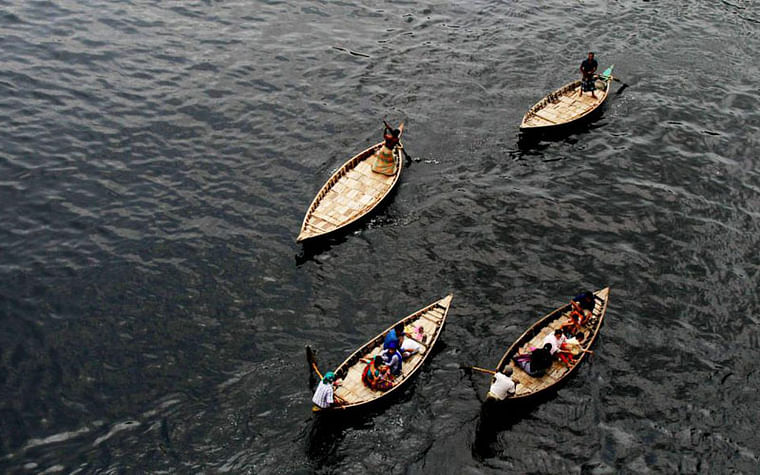 Boats sail on pitch black Buriganga river water polluted by industrial wastes. Photo taken in Babubazar bridge area of city by Saddam Hossain.