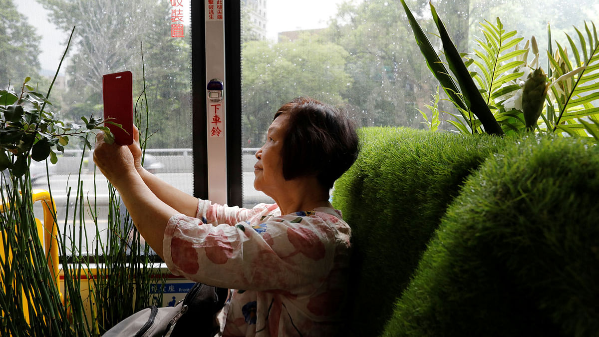 A passenger takes photo inside a plant-filled bus, a special route that runs for 5 days, featuring the concept of integrating more green space into cities, in Taipei , Taiwan. Reuters