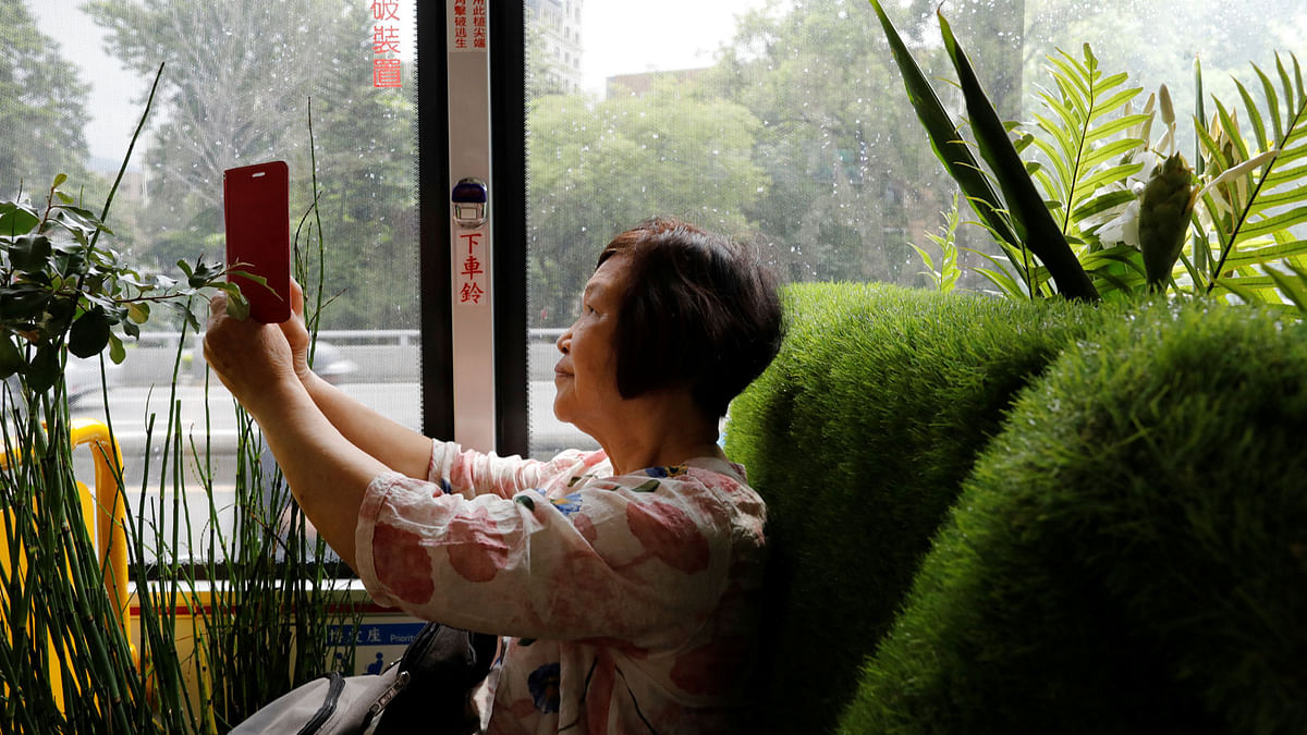 A passenger takes photo inside a plant-filled bus, a special route that runs for 5 days, featuring the concept of integrating more green space into cities, in Taipei , Taiwan. Reuters