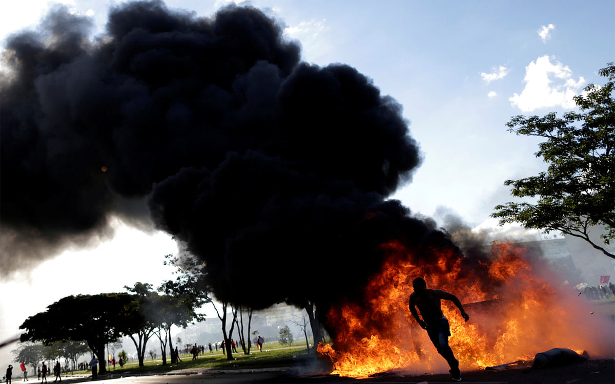 A demonstrator runs near a burning barricade during a protest against President Michel Temer and the latest corruption scandal to hit the country, in Brasilia, Brazil, May 24, 2017. Photo: Reuters