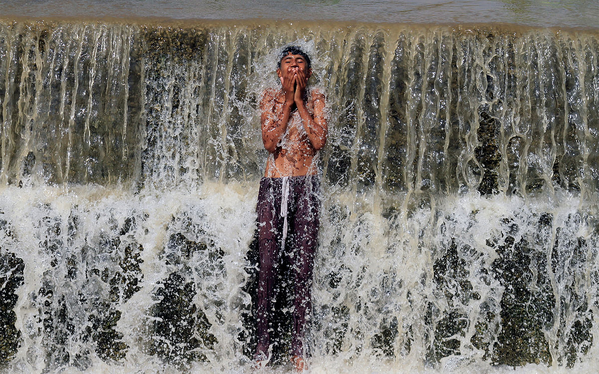 A boy bathes in a stream to cool off from the heat on a hot summer day in Swabi, Pakistan May 24, 2017. Photo: Reuters