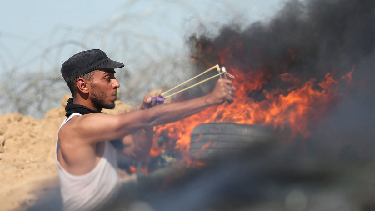 A Palestinian protester uses a slingshot to hurl stones towards Israeli troops during clashes near the border between Israel and Central Gaza Strip May 26, 2017. Photo: Reuters