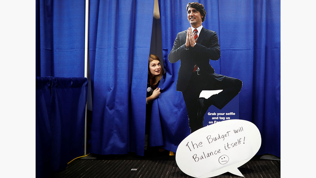 A woman peeks out of a curtain behind a cardboard cutout picture of Canada`s Prime Minister Justin Trudeau, at the Conservative Party of Canada leadership convention in Toronto, Ontario, Canada, May 27, 2017. Photo: Reuters